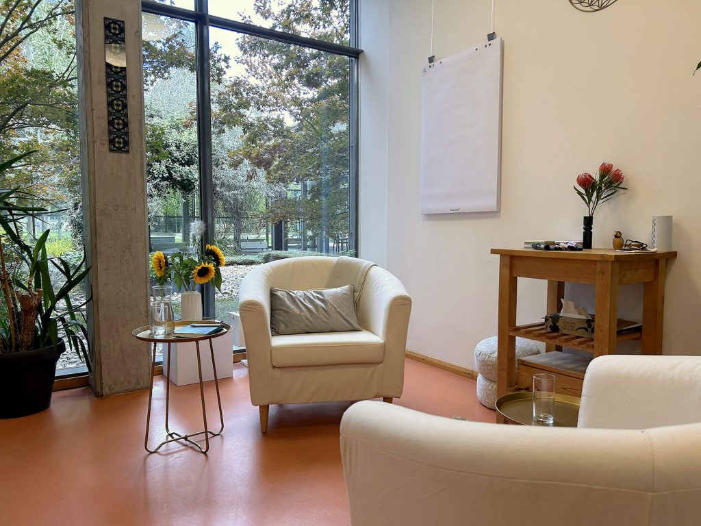 Abbildung des Coachingraumes von Tobias Krause. Gemütlicher heller Raum mit Fensterfront zu begrüntem Innenhof. Zwei bequeme Sessel stehen sich gegenüber.